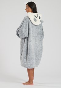 Ropa de casa de felpa gris de gran tamaño con una capucha blanca esponjosa que presenta un diseño de cara de oso y detalles en negro. Textura suave, hasta la rodilla, sin cierres.