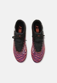 Zapatillas deportivas negras y multicolores con un patrón texturizado en forma de ola. Cuentan con cordones negros, acentos naranjas y un logo cerca del talón.