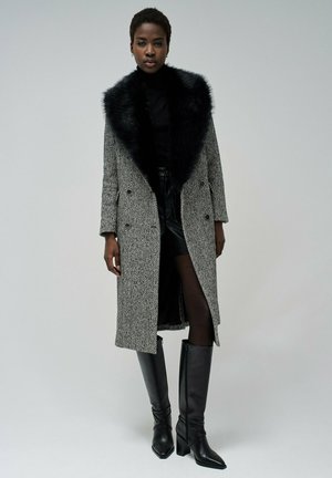 Gray houndstooth coat with a black faux fur collar, double-breasted design, paired with a black top, leather skirt, and knee-high boots.