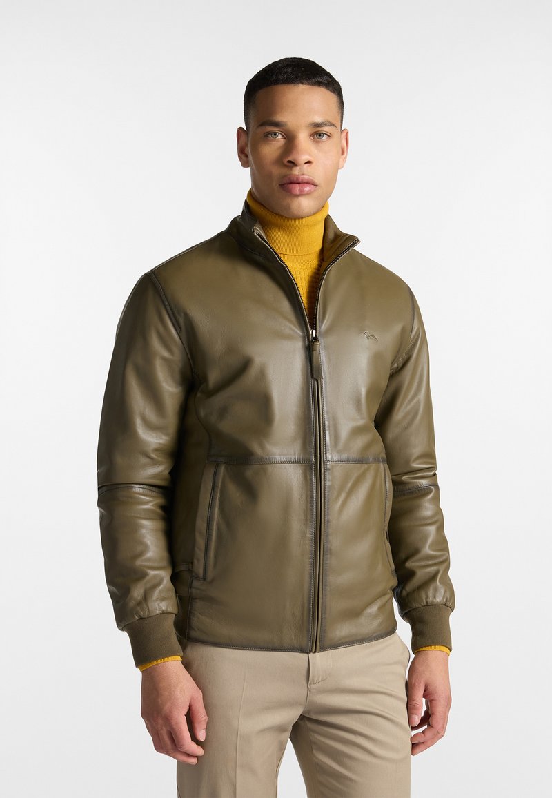 Olivengrüne Lederjacke mit hohem Kragen, Reißverschluss und zwei vorderen Taschen. Gerippte Bündchen in Dunkelgrün. Glatte Textur, minimale Markenkennzeichnung.