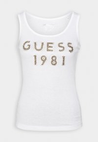 Débardeur blanc côtelé sans manches avec texte en sequins dorés "GUESS 1981" au centre devant.