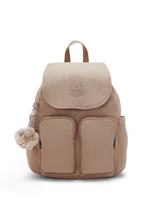 Zaino beige con due tasche frontali con zip, patta superiore, tasche laterali e un piccolo portachiavi con una scimmietta di peluche attaccato al lato sinistro.