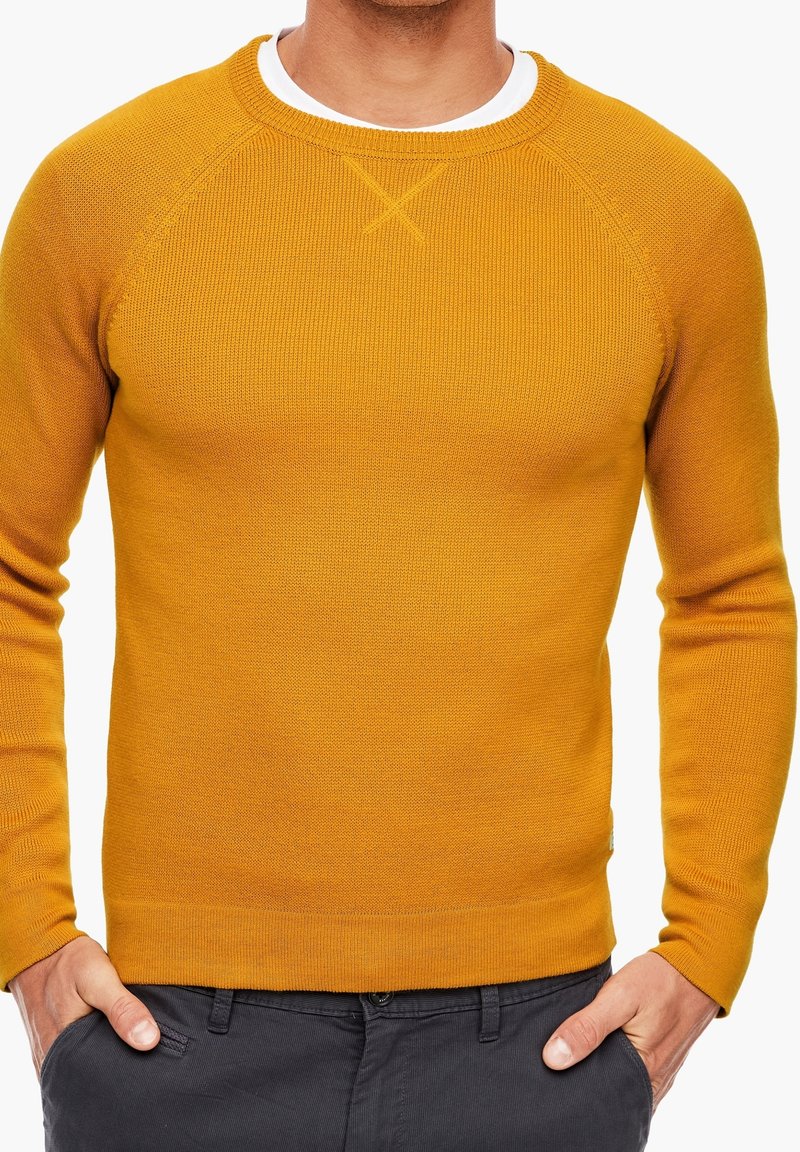 Senfgelber, gestrickter Pullover mit Rundhalsausschnitt, gerippter Struktur und Raglanärmeln. Mit einem dezenten Kreuzstichdetail am Hals.