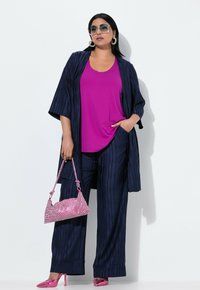 Námořnické pruhované kalhoty s širokými nohavicemi, které jsou spárovány s živě růžovým topem bez rukávů, ladícími růžovými lodičkami na vysokém podpatku, kabelem s kameny a oversized slunečními brýlemi.