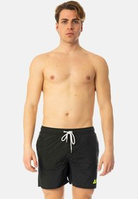 Shorts da nuoto neri con cintura elastica e cordino bianco, con un piccolo logo giallo neon sul lato sinistro. Tessuto liscio, lunghezza al ginocchio.