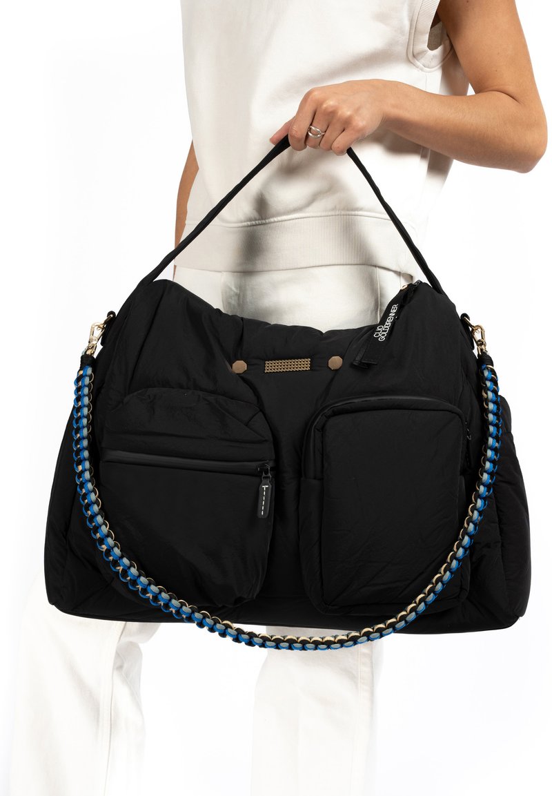 Black padded handbag with two front pockets, textured materials, and a woven strap featuring blue and gray accents. Zipper closures included.
