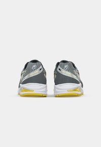 Gray athletic shoes with mesh upper, white sole, and yellow accents; features smooth texture and rounded heel design.