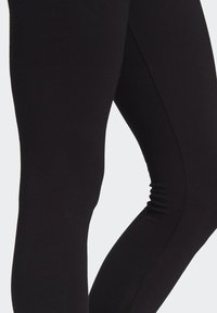 Svarta leggings tillverkade av elastiskt tyg, med en slät yta och kroppsnära design, lämpliga för vardags- eller sportklädsel.