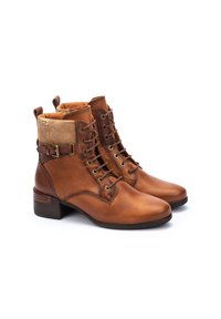 Botas de cuero marrón hasta el tobillo con un tacón grueso, panel lateral texturizado y cuello de pana. Presenta ojales metálicos y cordones para el cierre.