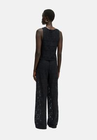 Zwart kanten twee-delig outfit met een mouwloze top met geometrische patronen en wijde broek met een vloeiende ontwerp.