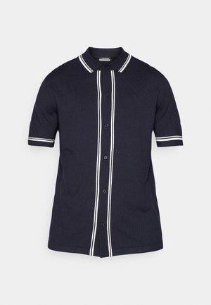 Ανοιχτό μπλε πλεκτό πόλο μπλουζάκι με κοντά μανίκια, λευκές ρίγες κατά μήκος του γιακα και της σειράς κουμπιών, διαθέτοντας πέντε κουμπιά και χαλαρή εφαρμογή.