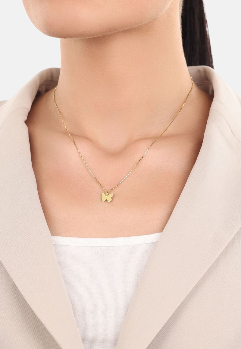 Goldene Schmetterling-Anhänger-Halskette an einer filigranen Kette, getragen über einem hellen Oberteil, mit glatter Textur und minimalistischem Design.