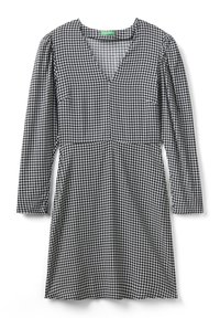 Abito a motivo houndstooth bianco e nero con maniche lunghe, scollatura a V e corsetto aderente che si trasforma in una gonna svasata.