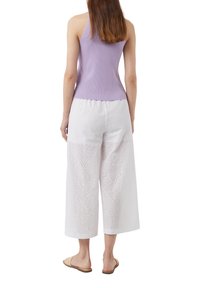 Lila geribbelde tanktop gecombineerd met witte wide-leg broek met oogjes borduursel en een ruime fit. Draagt met tan platte sandalen.