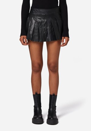 Black leather pleated mini skirt with a fitted waistband, smooth texture, and a flared silhouette. Paired with black combat boots.