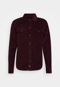 Burgunderfärgad kordflossskjorta med långa ärmar, knäppning framtill, två bröstfickor och krage. Har strukturerad tyg och kontrasterande knappar.