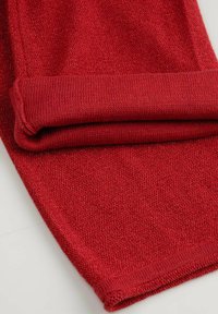 Czerwony dzianinowy materiał o fakturowanym splocie i wykończeniu z mankietem. Materiał ma delikatny połysk, który dodaje projektowi wizualnego zainteresowania.