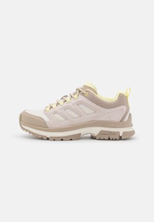 Lightweight hiking shoes with a beige and pale pink color scheme, featuring a textured upper, cushioned sole, and reflective accents.