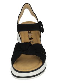 Sandalía de ante negra con diseño de frente anudado, talón abierto y correa ajustable. Cuenta con una plantilla acolchada beige y suela en capas blanca y negra.
