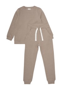 Sweatshirt beige et pantalons de survêtement assortis, fabriqués dans un matériau doux ; comporte un col rond, des poches latérales et une taille avec cordon de serrage.