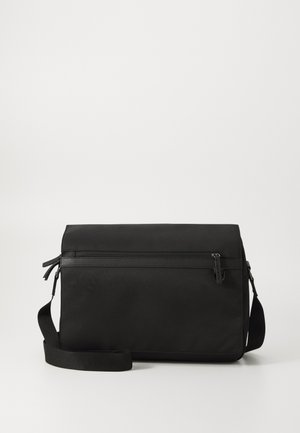 Sac messenger noir en tissu texturé. Comprend une poche avant zippée, une bandoulière ajustable et un design plat. Esthétique simple et moderne.