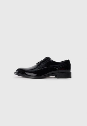 Scarpa da cerimonia in pelle verniciata nera con punta arrotondata, superficie liscia, design con lacci e tacco basso con dettagli logo sottili.