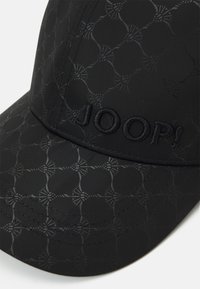 Black cap featuring a subtle geometric embossed pattern. The brand name "JOOP!" is embroidered on the front in a matching black thread.