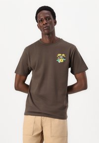Braunes Baumwoll-T-Shirt mit einem bunten Blumenmotiv und einer Krone. Kurze Ärmel, Rundhals-Ausschnitt, lockere Passform. Glatte Textur.