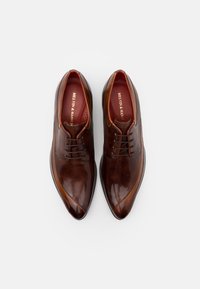 Chaussures habillées en cuir marron avec une finition brillante, design à bout pointu, fermeture à lacets à l'avant et une légère variation de texture sur les côtés.