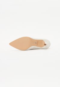 White high-heeled shoe with a pointed toe, textured upper, and a beige sole. Features a small heel and flat rear.