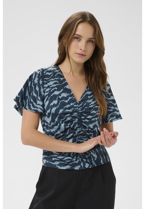 Krinka s kratkimi rokavi v temno modrem in svetlo modrem vzorcu. Ima V-izrez in nabran detajl spredaj. Lahka tkanina.