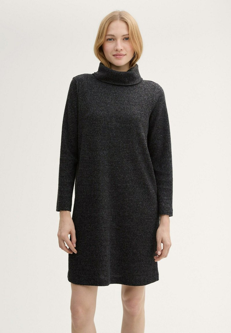 Schwarzes Pulloverkleid mit hohem Kragen, strukturiertem Stoff, langen Ärmeln und geradem Schnitt, das oberhalb des Knies endet.