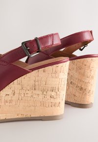 Rote Keilsandaletten aus Leder mit korkstrukturiertem Plateau. Verfügen über einen Schnallenriemen und ein glattes Lederoberteil.