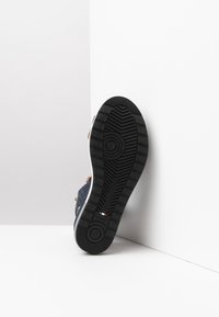 Sneaker mit einem Obermaterial aus navyfarbigem Canvas, braunen Lederakzenten, Gummisohle mit strukturiertem Griff und italienischer Flagge an der Seite.