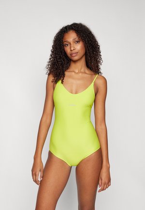 Maillot de bain une pièce vert néon avec un décolleté en V profond, des fines bretelles et un tissu extensible et lisse. Design minimaliste sans motifs visibles.