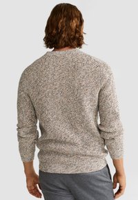 Beige Strickpullover mit mehrfarbigen Fasern. Besitzt einen klassischen Rundhalsausschnitt und lange Ärmel, die mit einem strukturierten Rippmuster versehen sind.