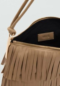 Borsa con frange in pelle beige, dotata di una zip superiore, interno nero e una piccola etichetta in rilievo. Texture liscia con dettagli di frange.