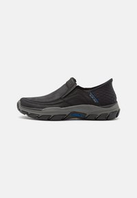 Black slip-on shoes with a smooth leather upper and textured fabric accent, featuring a cushioned sole with a gray rubber tread and blue branding.