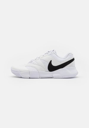 Sapatilha desportiva branca com um cabedal em pele texturizada, um logo swoosh preto e um colarinho almofadado. Conta com uma sola de borracha para aderência.