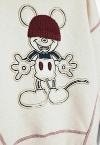 Sudadera crema con un ratón de dibujos animados bordado que lleva un gorro de lana burdeos, con detalles contorneados en azul oscuro y acentos rojos.