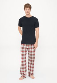 Schwarzes T-Shirt mit kurzen Ärmeln und rot karierte Schlafanzughose mit weißen, grünen und schwarzen Mustern; aus Baumwollstoff; lässige Passform.