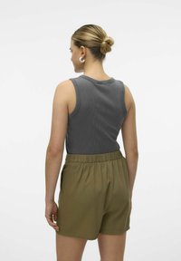 Grijze ribgebreide mouwloze top gecombineerd met olijfgroene high-waisted shorts met een elastische tailleband en zijzakken.