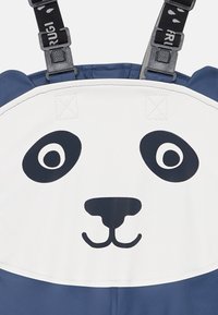 Panda-tema overall med en hvit topp som har et pandaansikt, svarte øyne og nese, og en blå bunn. Justerbare stropper inkludert.