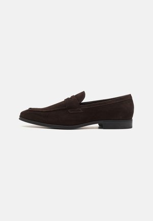Dark brown suede men's loafer with low heel, rounded square toe, and strap detail across the top, shown in side profile on white background.