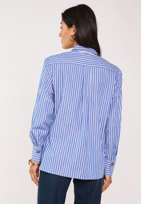 Camicia a righe con strisce verticali blu e bianche, polsini con bottone, colletto classico e vestibilità rilassata, realizzata in tessuto leggero.