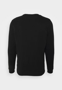 Melna pelēka ar garām piedurknēm, apaļu kakla izgriezumu un ribota apakša. Izgatavota no mīkstas auduma ar gludu tekstūru. Nav redzamu logo vai rakstu.