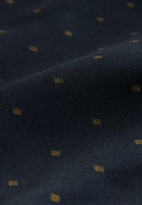 Dunkelblauem Stoff mit einer strukturierten Oberfläche, die kleine gelbe Punkte in einem verstreuten Muster zeigt. Glattes und strapazierfähiges Material.