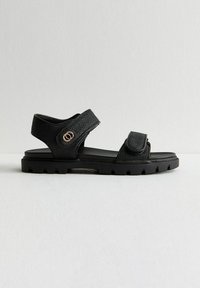 Svarta sandaler med texturerade syntetiska remmar, justerbar kardborrestängning och en kraftig gummisula med ett mönster för bättre grepp.