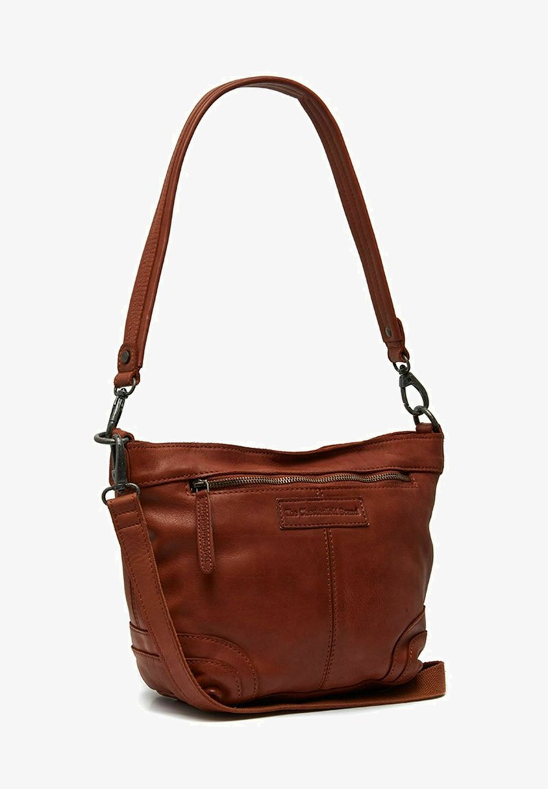 Bruine leren schoudertas met een enkele schouderband, een ritszak aan de voorkant en een gestructureerd detail. Voorzien van metalen hardware en een compact ontwerp.