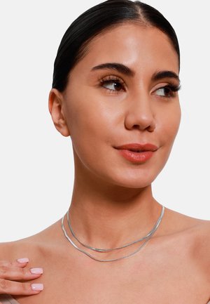 Collana in argento a strati con design ondulato, caratterizzata da tre fili di spessore variabile. Texture liscia, leggera e dall'aspetto minimalista.